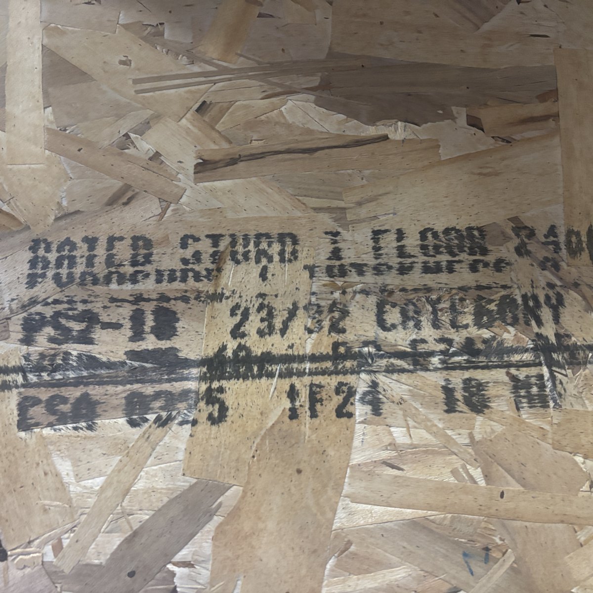 Mill grade stamp on 23/32 inch tongue-and-groove OSB subfloor sheathing showing panel grade and certification markings